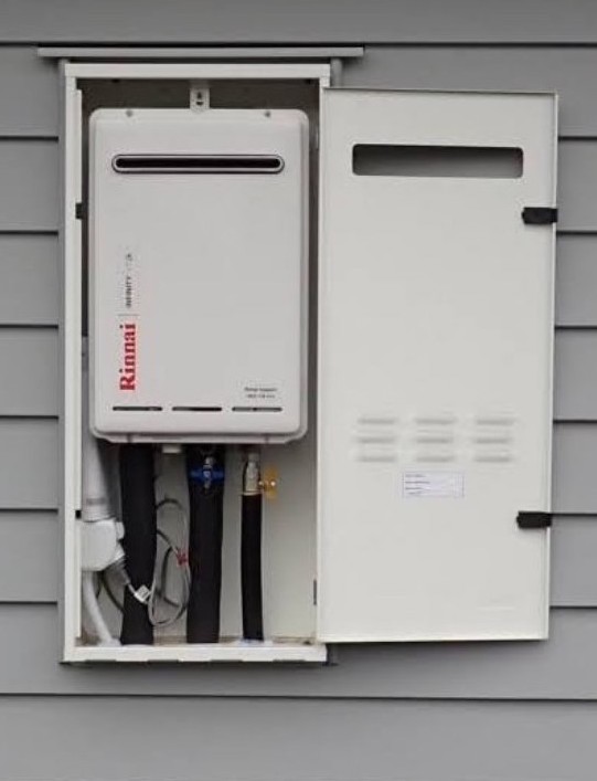 Photo show an Infinity hot water system cabinet recessed into exterior wall of house